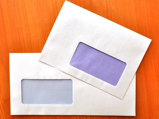 Two empty, letter-sized envelopes against a wood grain background