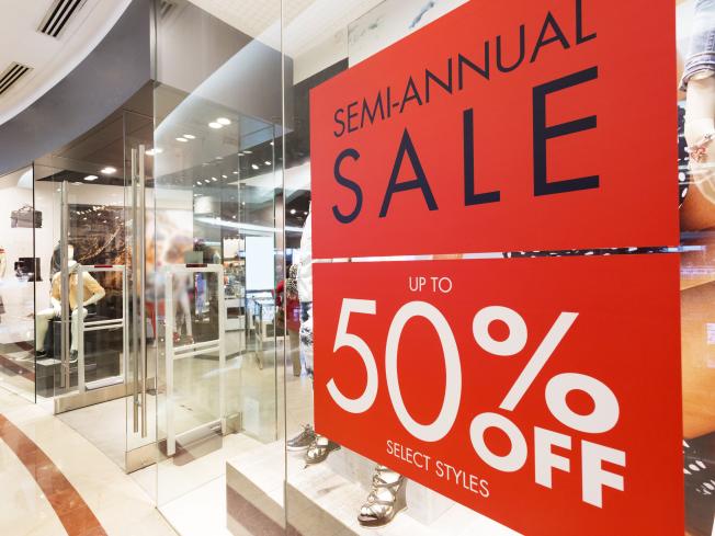 A closeup of a sale sign in a clothing store window