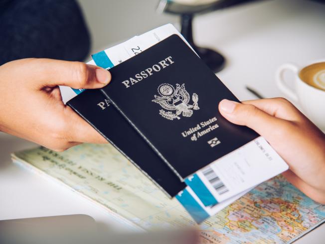 A closeup of a traveler handing over two United States passports